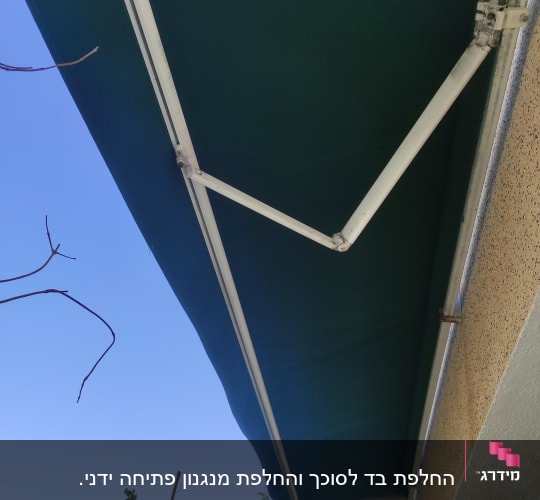 סוכך ירוק עם מסגרת מתכת לבנה על קיר